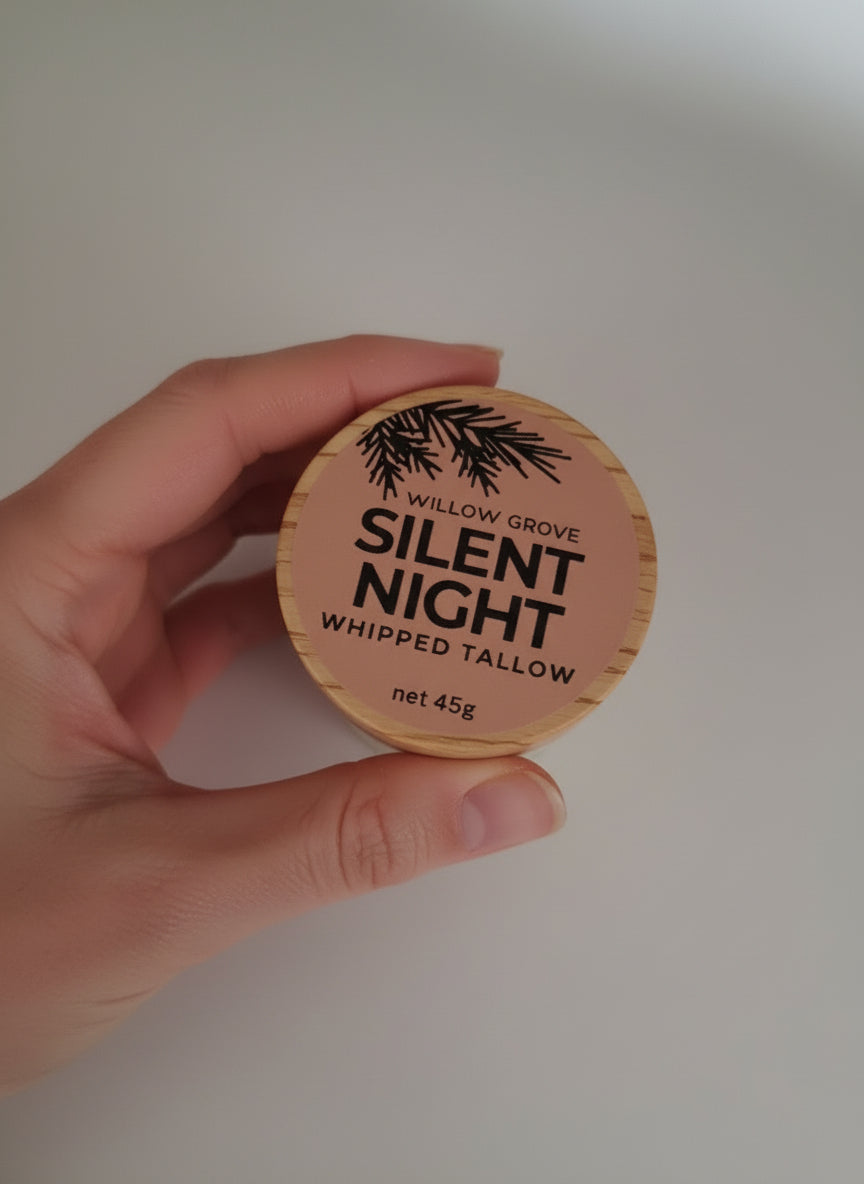Hand holding a container of Willow Grove Silent Night whipped tallow against a plain background