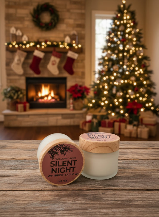 Two jars of tallow labeled 'Silent Night' on a wooden surface with a Christmas tree and fireplace in the background.